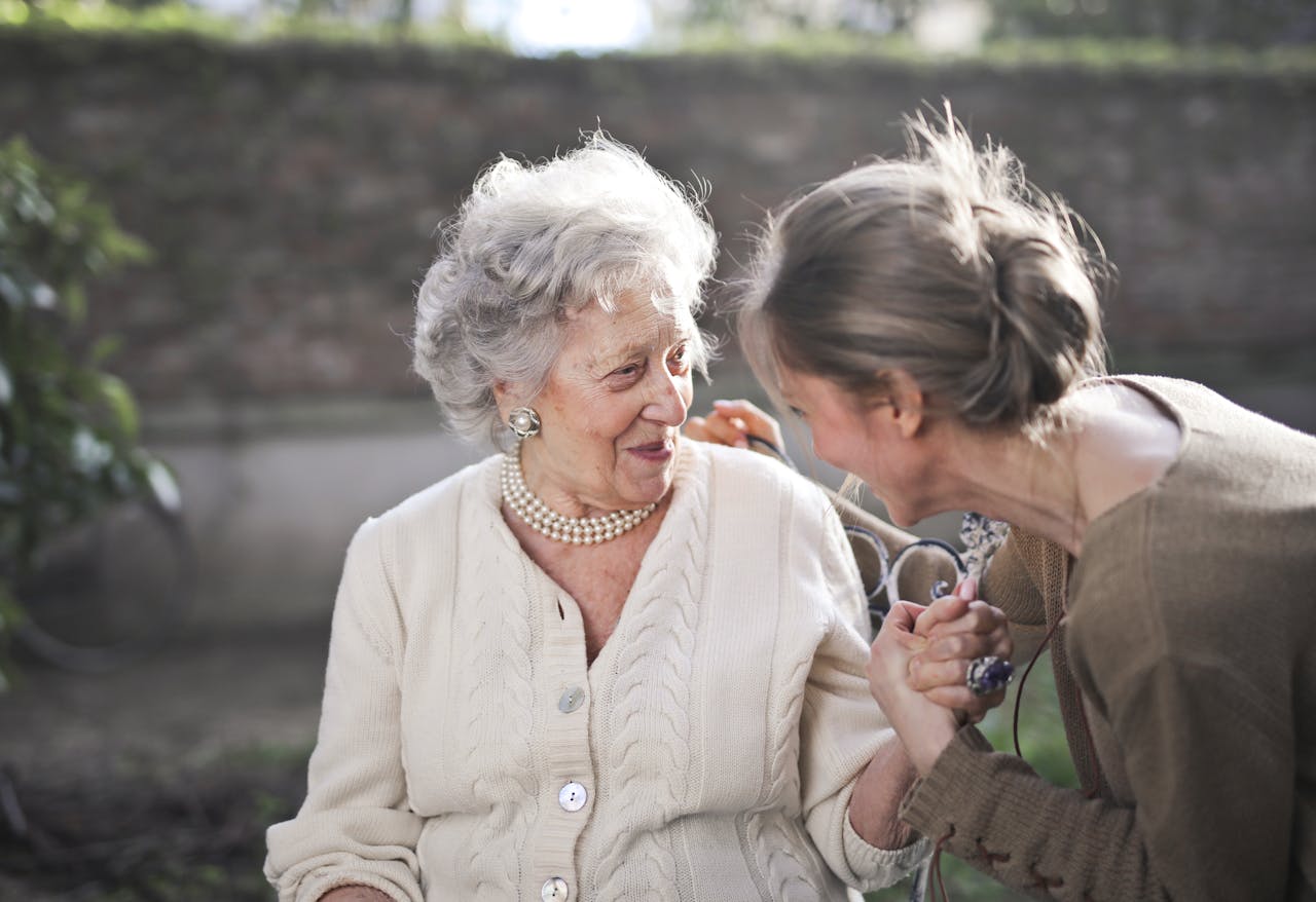creative-02 Joyful interaction between an elderly woman and her granddaughter in a sunny outdoor setting.