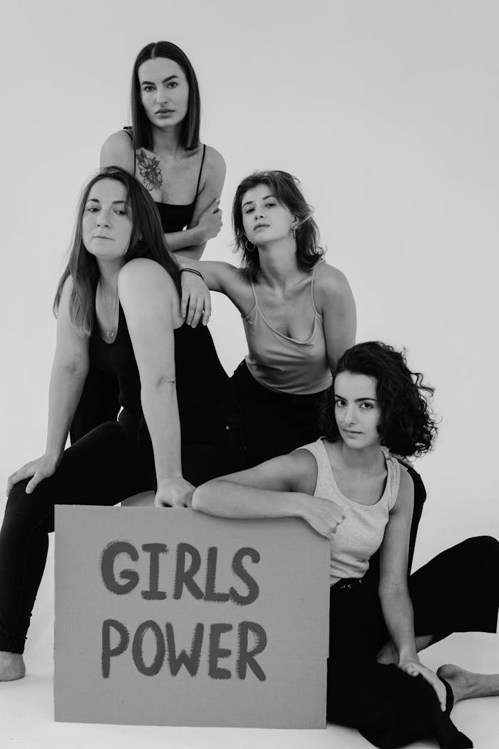 brand-01 Black and white studio shot of diverse women posing with a 'Girls Power' sign, celebrating feminism and friendship.