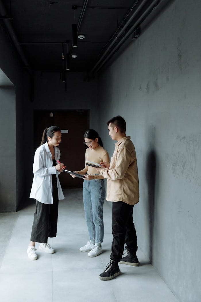 Services-03 Three young professionals engaged in a team discussion inside a modern office hallway.