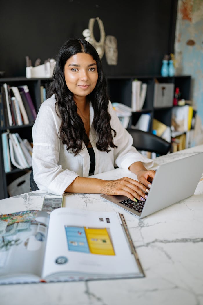 Services-01 Confident woman in modern office setting working on a laptop, embodying professionalism and focus.