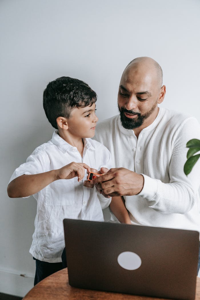 Father and son enjoying technology time together at home using a laptop.